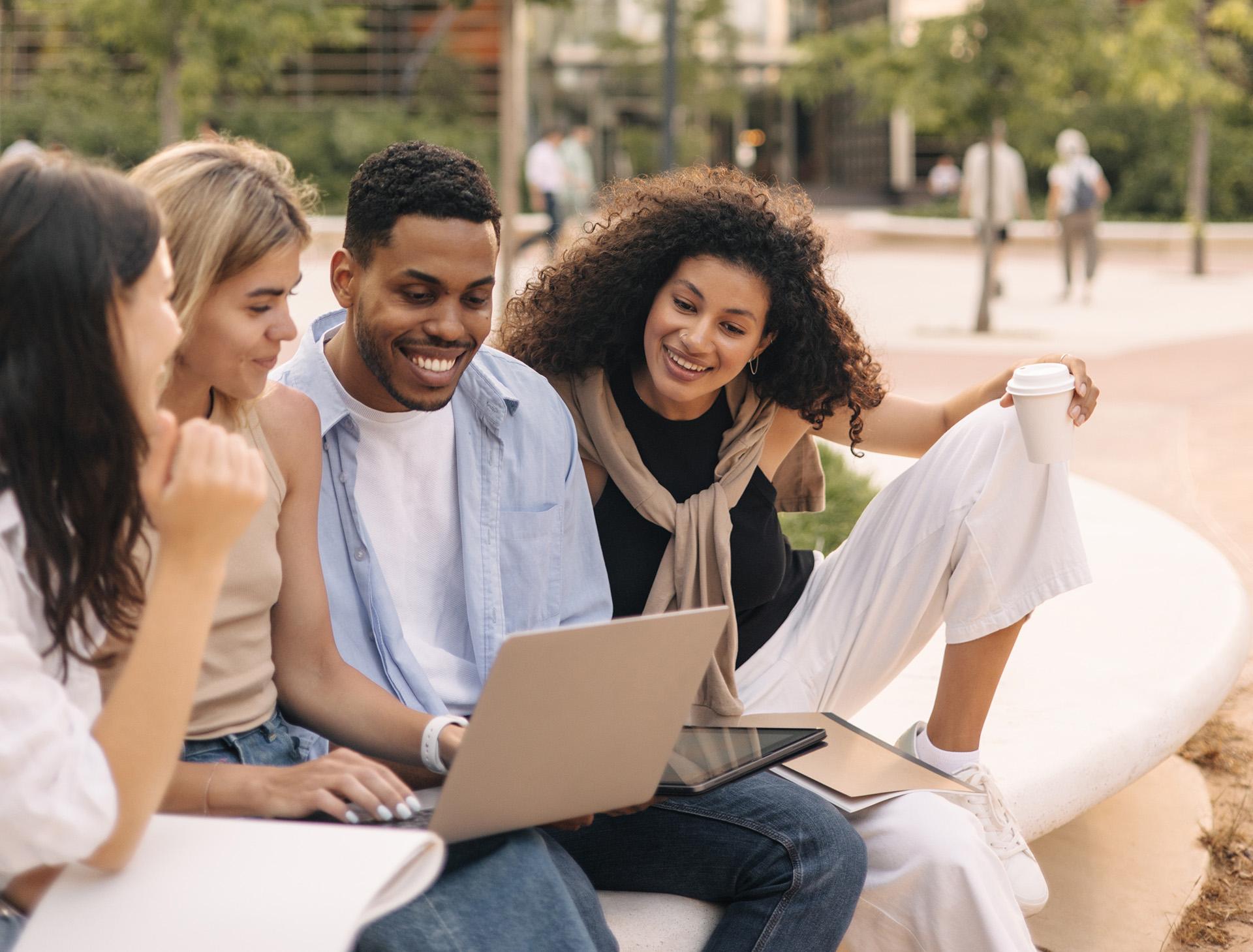 Menschengruppe mit lächelndem Blick auf einen Laptop